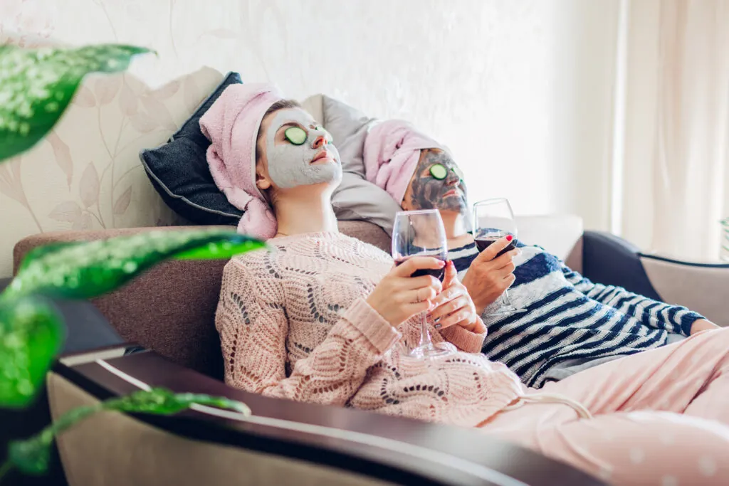 Two friends in face masks with glasses of wine